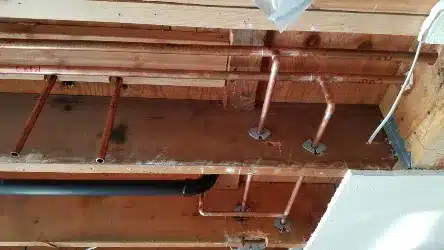 Whole-House-Repipe-scaled (1) Ceiling view of copper hot and cold water pipes routed through joists with labeled directions