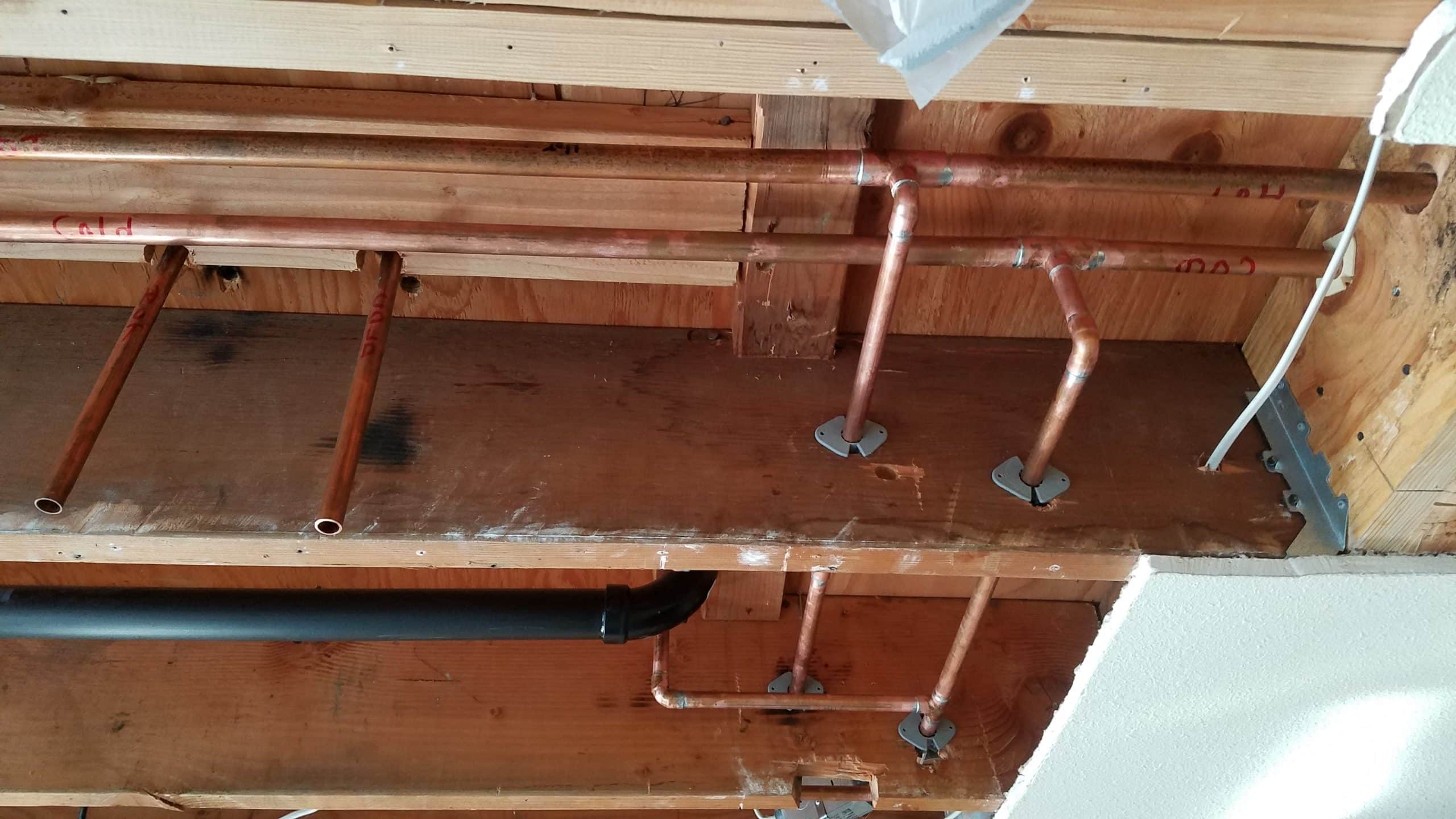 Whole House Repipe Ceiling view of copper hot and cold water pipes routed through joists with labeled directions