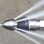 Hydro jetting sewer nozzle spraying high-pressure water jets.