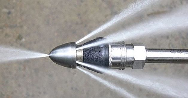 Hydro jetting sewer nozzle spraying high-pressure water jets.